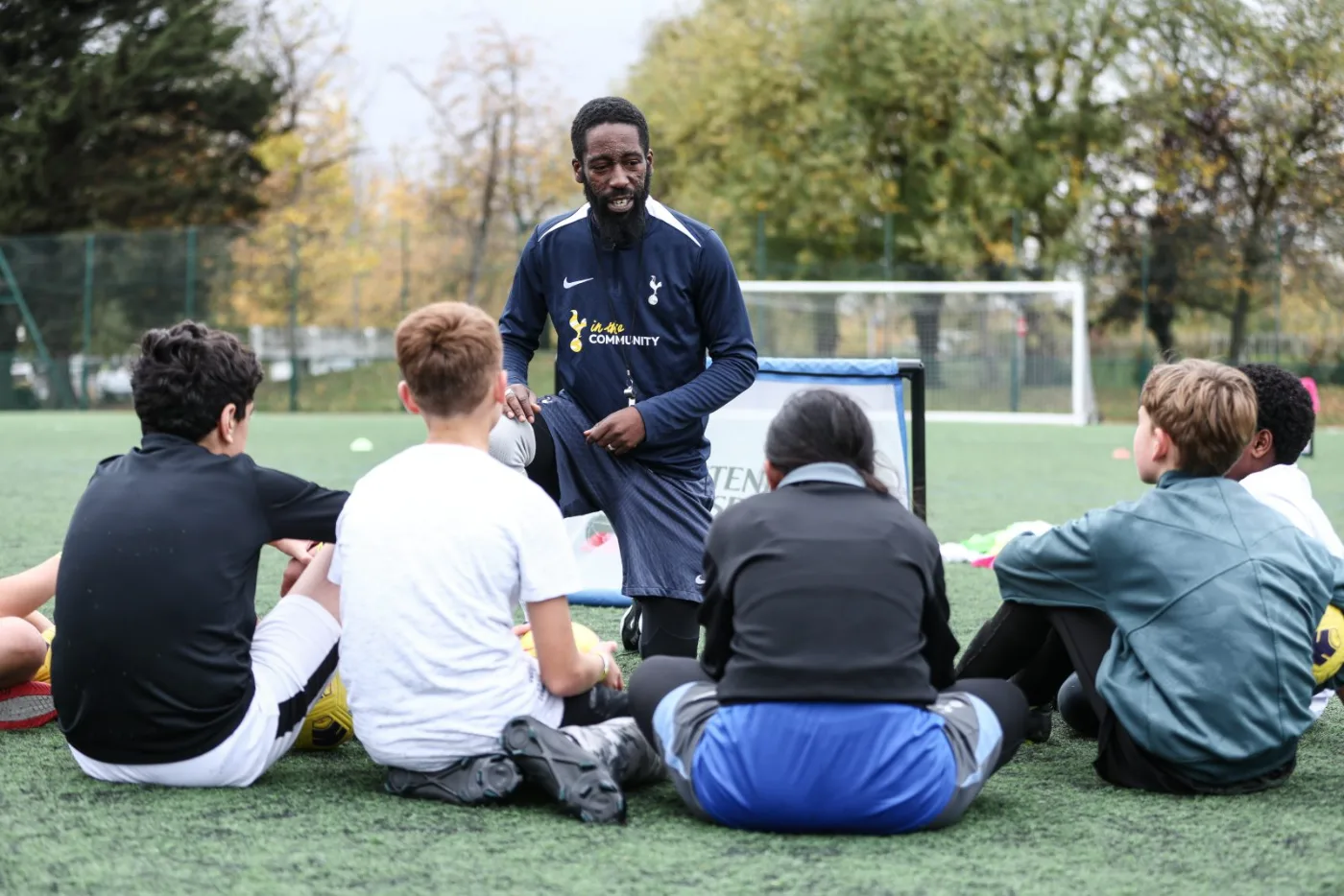 A coach leading an outdoor football session on the pitch