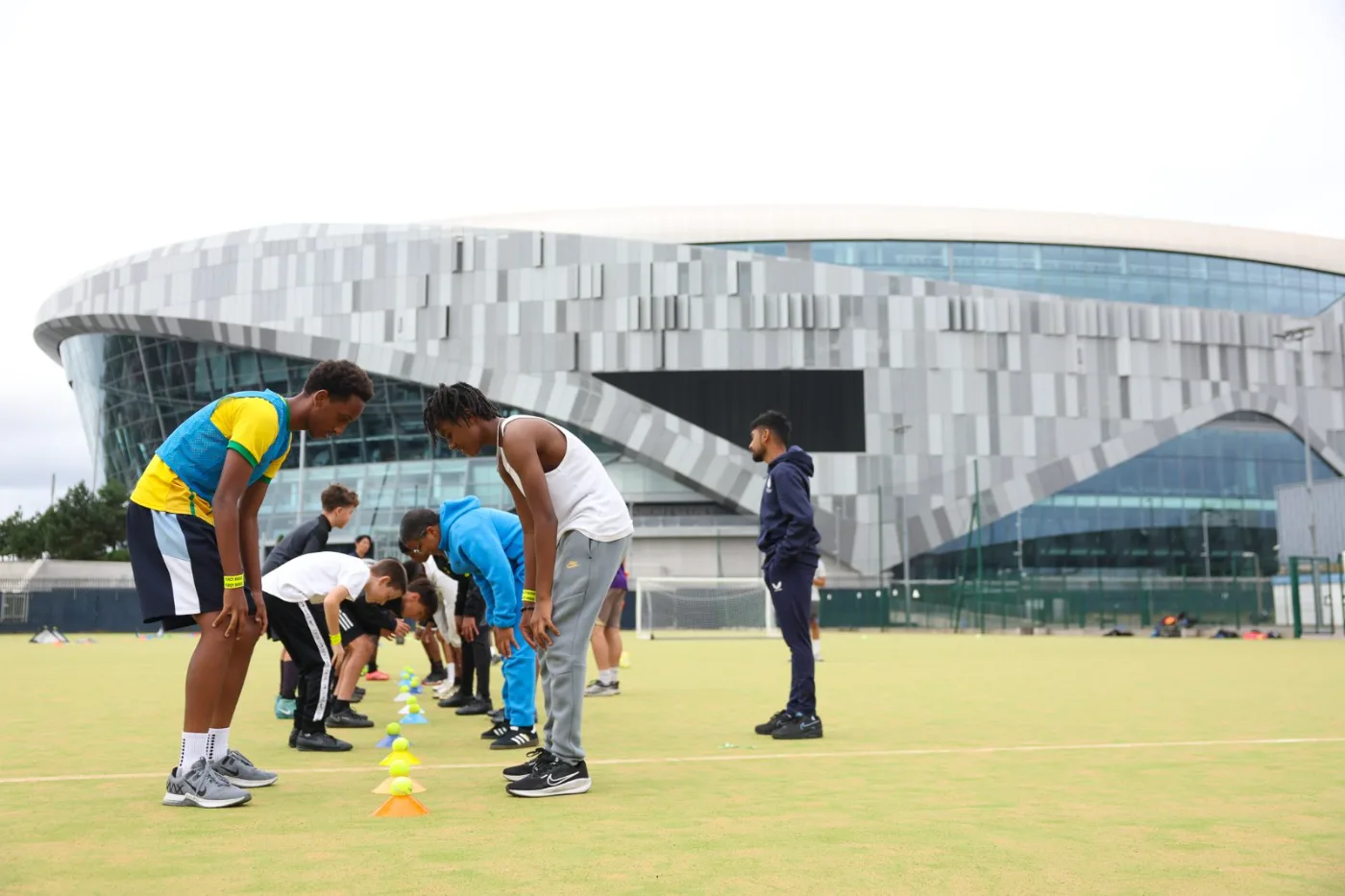 A coaching huddle at Dukes Aldridge Academy, N17, with Tottenham Hotspur Stadium behind