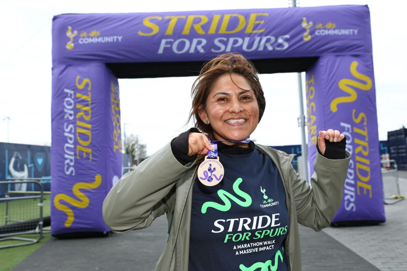 A Stride for Spurs walker celebrating with her medal at the finish arch